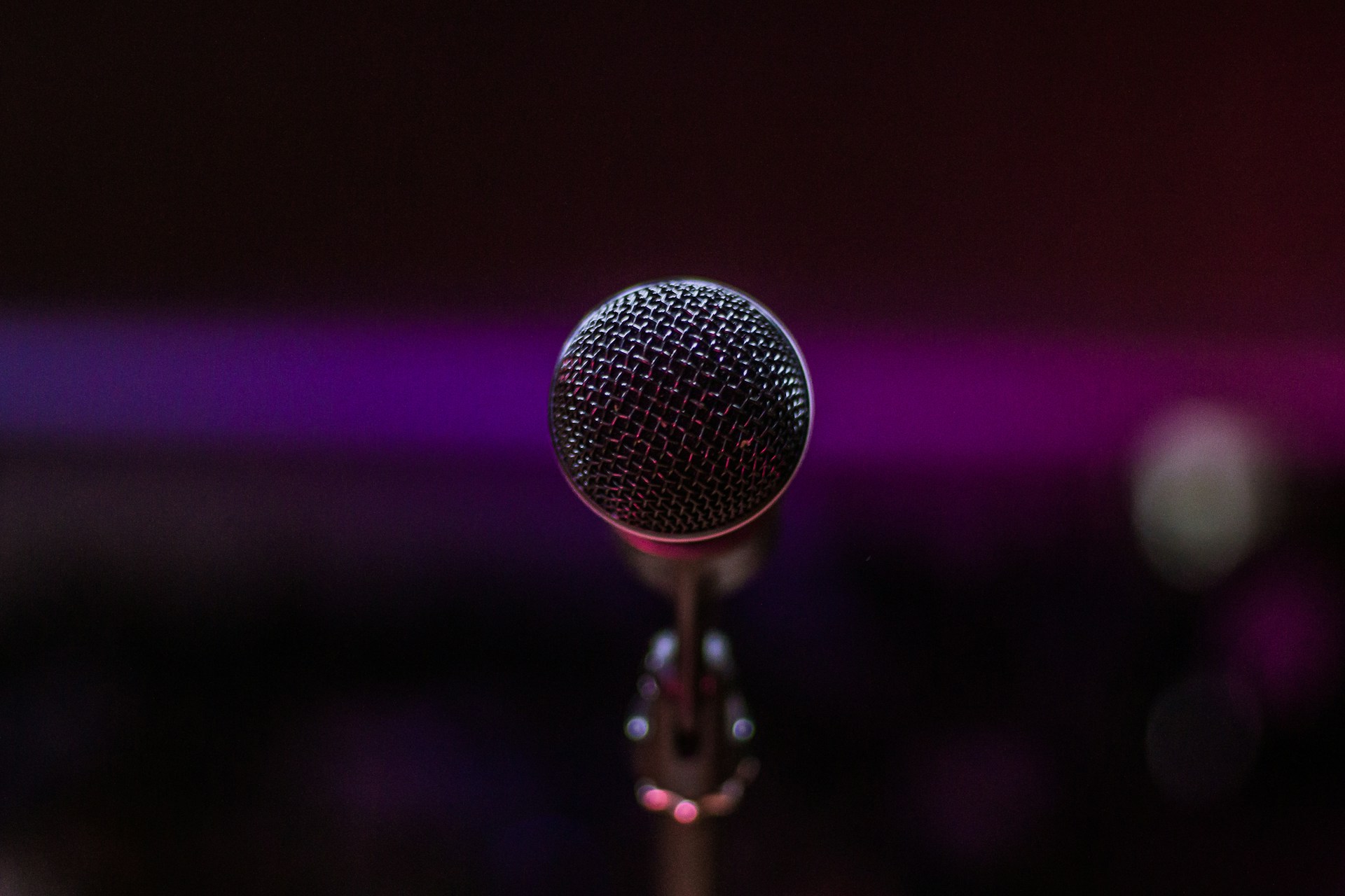 A photo of a stage microphone against a purple backdrop